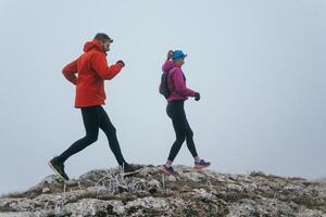 Trail running couple man and woman running on a mountain path photo