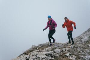 Trail running couple man and woman running on a mountain path photo