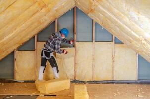 Worker Installs Mineral Wool Insulation in Residential Attic During Daylight Hours photo