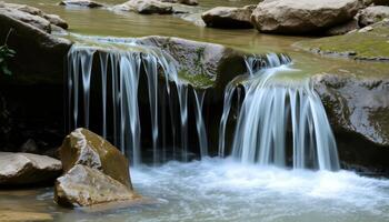 Small Waterfall Cascading Over Mossy Rocks in a Natural Stream photo