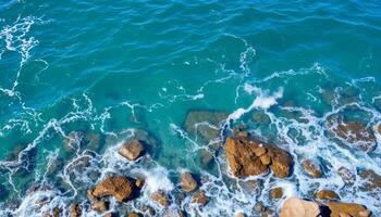 Aerial View of Turquoise Ocean Waves Crashing on Rocky Shore photo