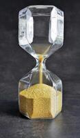 Close up Hourglass with golden Sand in dark background, Every second count, running out of time or time up or passage of time concept photo