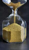Close up transparent Hourglass Falling golden Sand in dark background, Every second count, running out of time or time up or passage of time concept photo
