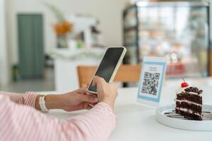 Woman use smartphone to scan QR code to pay in cafe restaurant with a digital payment without cash. Choose menu and order accumulate discount. E wallet, technology, pay online, credit card photo