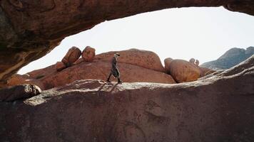 Man Walking Under Rock Arch in African Desert video