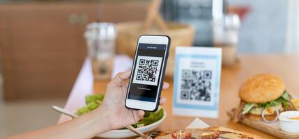 Woman use smartphone to scan QR code to pay in cafe restaurant with a digital payment without cash. Choose menu and order accumulate discount. E wallet, technology photo