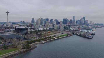 Aerial view of downtown Seattle, showcasing skyscrapers, Columbia Center, ferries at the terminal, a red sculpture, and industrial cranes under clouds. video