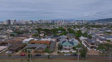 Aerial view of a suburban neighborhood on Oahu island, Hawaii, with tree lined streets, green spaces, and the Honolulu skyline near the Pacific Ocean. video