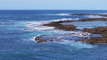 Aerial view of Shark's Cove on Oahu Island, Hawaii, showing rocky shoreline, turquoise tide pools, swimmers, and waves crashing against the rocks. video