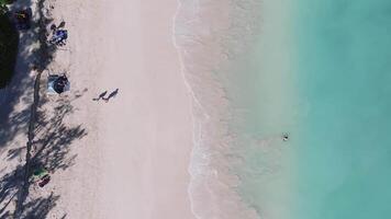 Serene aerial view of a beach on Oahu Island, Hawaii, with turquoise waves, sandy shore, beachgoers, a yellow kayak, and scattered beach gear. video