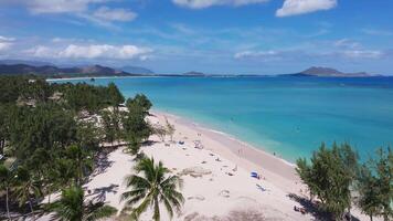 Sweeping aerial pan over a pristine beach on Oahu Island, Hawaii, with turquoise waters, white sand, palm trees, and Diamond Head in the background. video