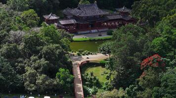 A serene aerial view of the Byodo In Temple in Oahu, Hawaii, showcasing its traditional Japanese architecture surrounded by dense forest and greenery. video