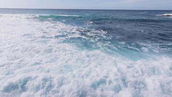 Serene aerial view of the North shore Pacific Ocean near Oahu, Hawaii, with vibrant blue waves rolling under a partly cloudy sky, showcasing a tranquil seascape. video