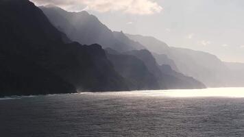 Slow aerial pan of Napali Coast on Kauai Island, Hawaii, showcasing jagged cliffs, lush greenery, and the Pacific Ocean under sunlight. video