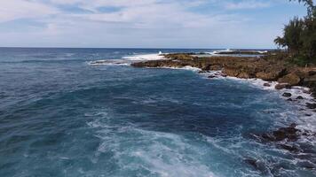 Aerial view of Oahu's rocky North shore coastline in Hawaii, with waves crashing against volcanic rocks. Turquoise waters and white surf create a dynamic scene. video