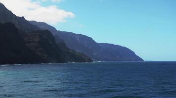 Aerial view of the Napali Coast on Kauai Island, Hawaii, with jagged cliffs, lush greenery, turquoise waters, and gentle ocean waves in motion. video