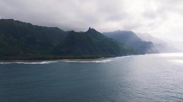 Aerial view of the Napali Coast on Kauai Island, Hawaii, featuring jagged cliffs, lush greenery, ocean waves, and a slow pan along the coastline. video