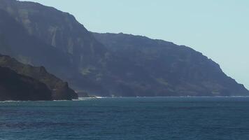 Aerial view of the Napali Coast on Kauai Island, Hawaii, with rugged cliffs, turquoise ocean, and gentle waves lapping at the cliff base. video