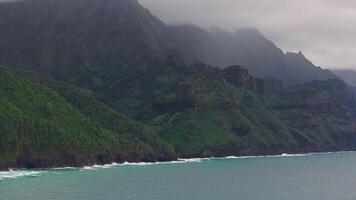 Serene aerial view of Napali Coast on Kauai Island, Hawaii, with dramatic cliffs, lush greenery, and gentle motion over the ocean and misty light. video