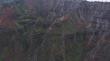Aerial view of Waimea Canyon on Kauai Island, Hawaii, with lush forests, red cliffs, drifting mist, and a reflective body of water. video
