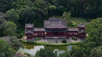 antenn se av byodo i tempel i åh, hawaii, omgiven förbi frodig grönska och en damm. de kamera rör sig mjukt, highlighting dess arkitektur. video