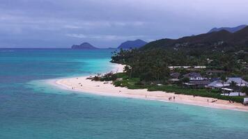 A slow, sweeping aerial pan of Lanikai Beach on Oahu Island, Hawaii, featuring turquoise waters, white sand, lush greenery, and the Mokulua Islands. video