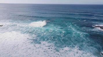 Aerial view of dynamic ocean waves crashing and spreading, creating white foam patterns on the turquoise water near Oahu, Hawaii. video