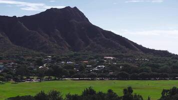 Sweeping aerial view of Oahu, Hawaii, featuring Diamond Head crater, urban greenery, scattered buildings, and a dome shaped structure under clear skies. video