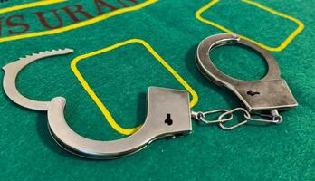 Handcuffs placed beside poker chips on a table at a dimly lit gambling setting photo