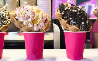 Bubble Waffle cone. Close-up of Assorted Ice Cream Cones with different flavors of ice creams, cookies and sprinkles in a Display in an ice cream Store photo