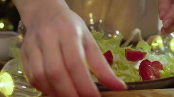 Housewife prepares refreshing salad of iceberg lettuce and cherry tomatoes. She carefully arranges ingredients on plate, using her hands to create beautiful presentation. video