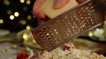 A close-up shot of a piece of parmesan cheese, which the chef grates and adds to the caesar salad with chicken and vegetables. Slow motion video