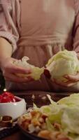 une grand iceberg salade ou chou feuille est pelé et pièces sont déchiré de à faire une délicieux salade avec tomates et Croûtons. vertical. video