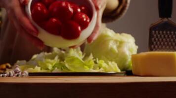 To prepare salad, cook pours handful of fresh, juicy, ripe cherry tomatoes onto cutting board to slice them for the salad. Slow motion video