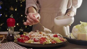 Sauce and dressing are added to large bowl of Caesar salad, which is prepared as part of festive Christmas feast. This gives salad its unique taste. video