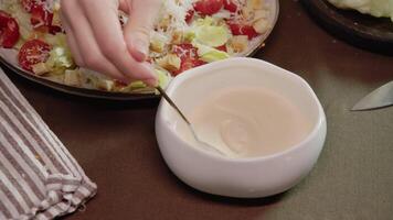 Cook prepares white sauce based on sour cream, mayonnaise, and garlic, which is suitable for various salads. housewife prepares this sauce for Caesar salad. video