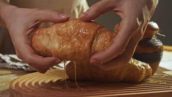 Delicious and sweet croissant, drizzled with maple syrup, honey or molasses, is broken in half to reveal chocolate filling with cocoa and divided into two portions. video