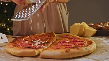 Baker begins to sprinkle base of an Italian pizza baked with tomatoes and grated cheese to continue baking process and allow cheese to melt. video