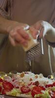 Detailed view of piece of parmesan cheese, which the chef grates and incorporates into the caesar salad with chicken and vegetables. video