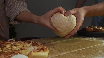 Family, deeply in love, is preparing pizza using dough. They intertwine their hands, forming heart, gesture that represents their passion for baking and cooking. video