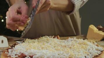 a lot of yellow and delicious cheddar cheese is grated and crushed during the preparation of four cheese pizza. slow motion video
