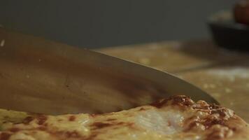 Surface of pizza, which is covered in melted delicious parmesan and mozzarella cheese, is sliced into pieces with sharp knife before being served in Italian restaurant. video