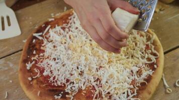Cheese is grated and the crumbled pieces are sprinkled on top of the pizza, which is baked with tomatoes according to traditional Italian recipe. top view video