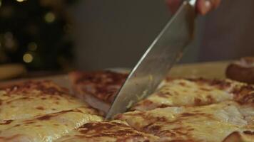 Surface of pizza or khachapuri covered with melted crunchy cheese is cut into equal portions with sharp knife. video