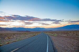 Scenic desert road at sunset with colorful clouds and mountain backdrop n photo
