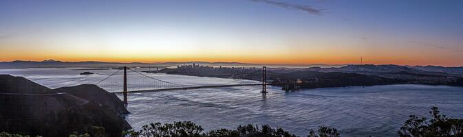 Golden Gate Bridge at sunset with San Francisco skyline in the background l photo