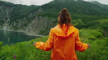 Woman Traveling In Beautiful Nature, Back View Of Lady In Orange Raincoat Walking On High Shore video