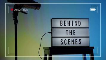 Behind the scene light box in front of vdo camera frame. Black text on white lightbox of word Behind the scenes. Prop for filmmaker movie or film studio. Footage for B roll film production making of video