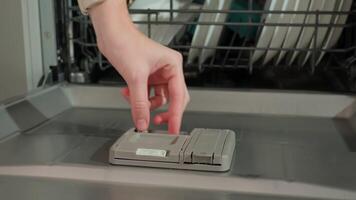 Hand placing dishwasher detergent tablet into dispenser of open dishwasher video