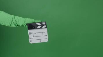 Mini Movie Clapper board clapped by Hand. on green screen camera background. Filmmaker hit film slate on green camera frame. Clapperboard Chroma key suit shooting. Green screen composite vdo produce video